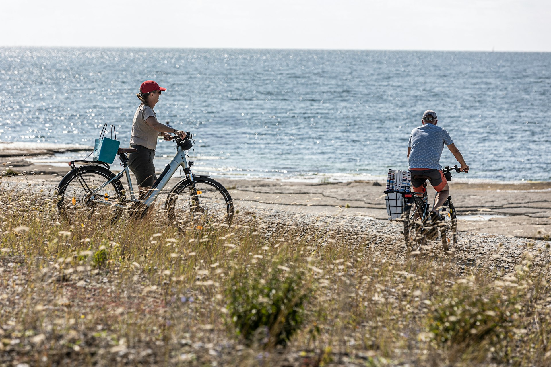 Two people cycling along the ocean shore.